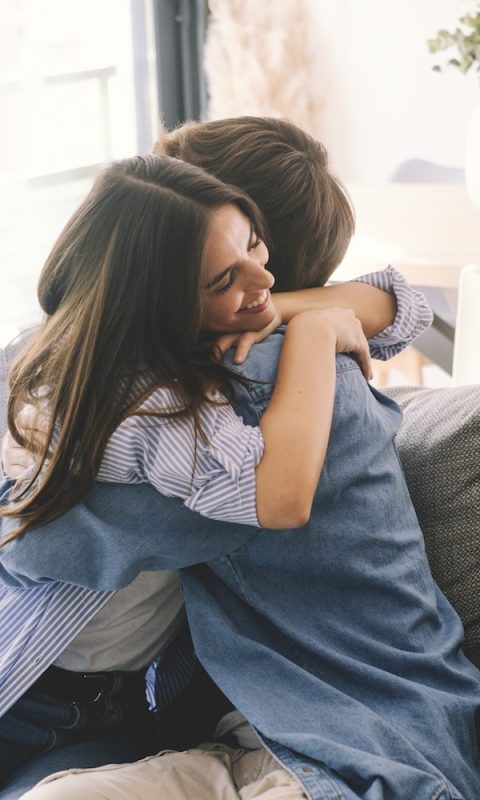 Beautiful young couple hugging in their new apartment. Engaged couples celebrate by hugging each other happily for their new home. Celebrating relationship achievement man and woman indoor leisure