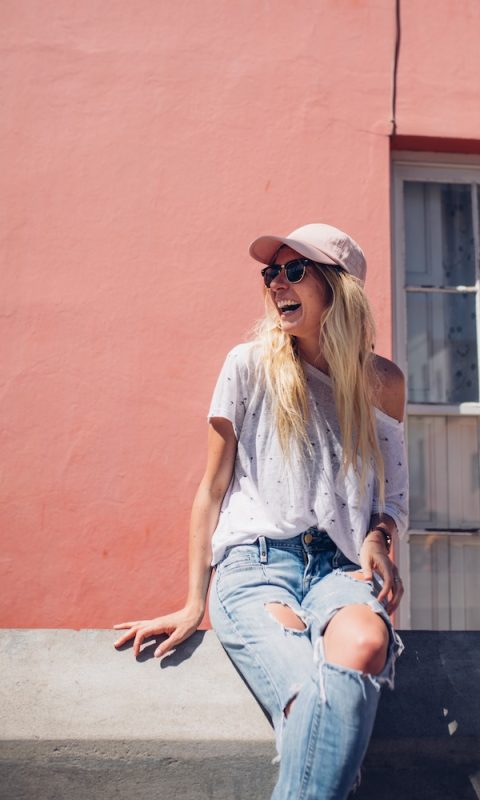 cheerful-young-woman-sitting-against-wall