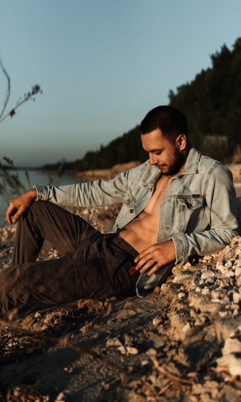 young-man-looking-away-while-sitting-land